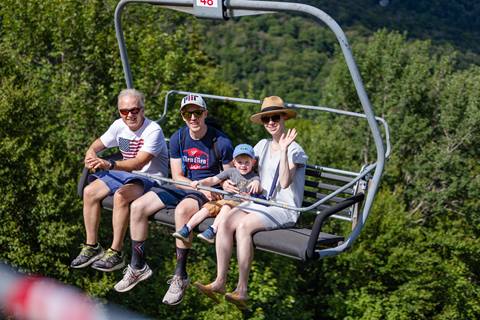 A family in the summer happy riding up the chairlift 