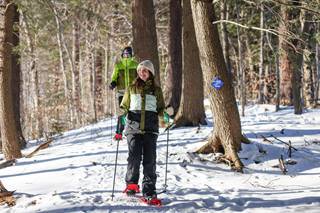 a woman snowshoeing through the woods 