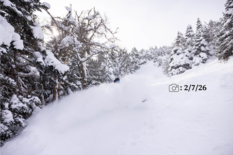 Snowboarder wearing a black helmet in powder