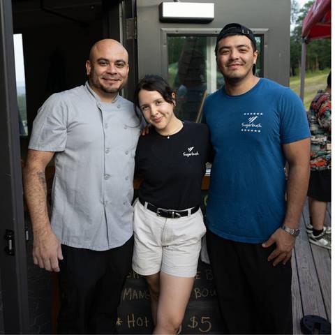Three staff members standing at an open door outside smiling. 