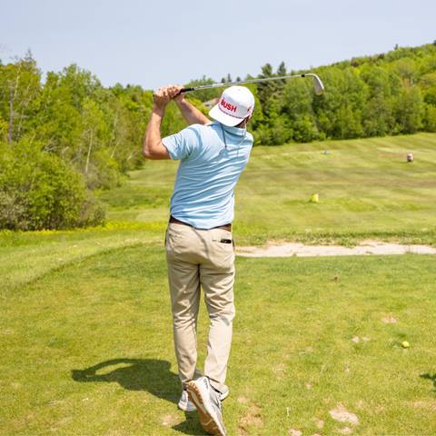 A golfer teeing off wearing a Bush hat 