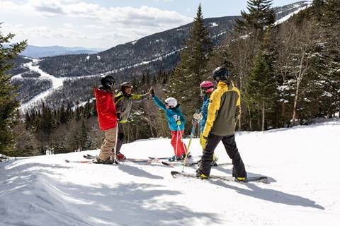 A group of skiers standing and giving a high five 
