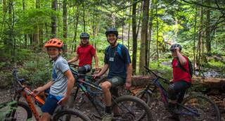 A group of four kids with their mountain bikes in the woods