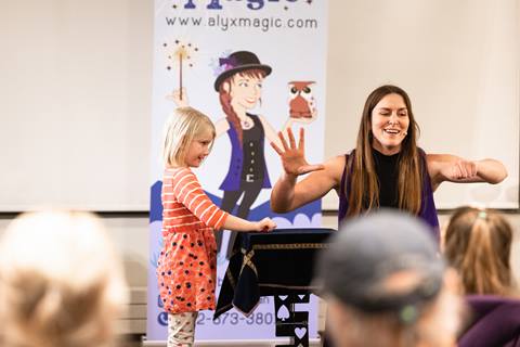 alyx the magician does a trick with a little girl