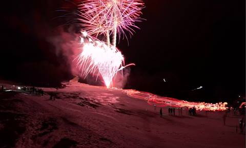fireworks go off while skiers come down the mountain