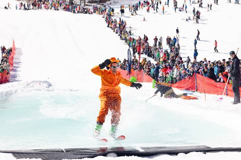 man in orange making it across pond on skis
