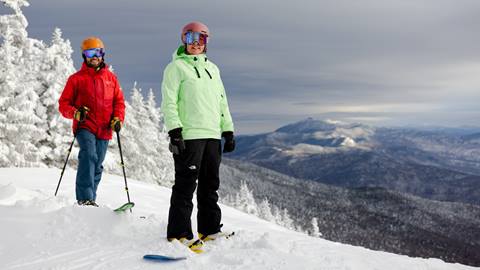 A skier and snowboarder smiling at the camera