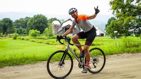 A gravel biker holding up a peace sign