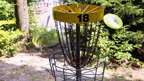Disc Golf basket with a disc going in 