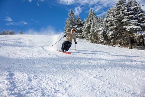 Skier in front of blue skies at Mt Ellen on opening day