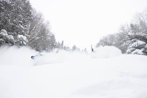 Skiers and snowboards riding deep powder as a group
