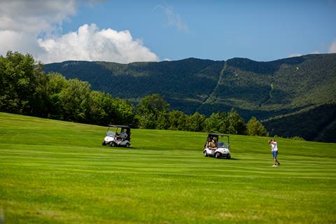 Group golfing in front of a mountain backdrop