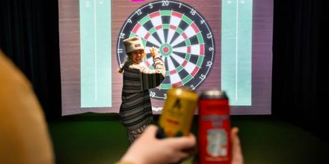 Folks cheersing in front of a giant dart board with a women smiling