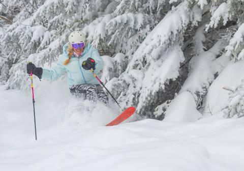 Women skiing powder in a blue jacket 