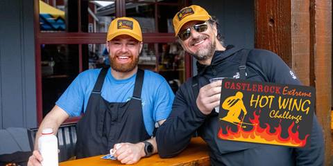 two men smiling with glass of milk after completing hot wing challenge