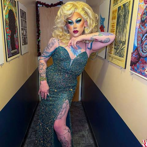 photo of drag queen marjorie in a blue dress posing in a hallway