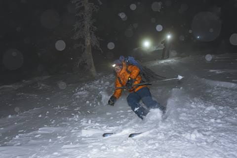 skier skiing at night with headlamp and rucksack