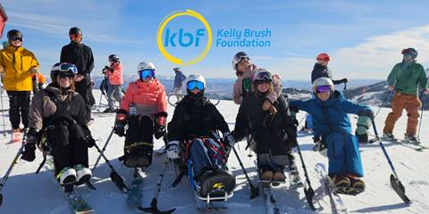 a photo of adaptive skiers smiling at camera at mountain top with kbf logo overlay