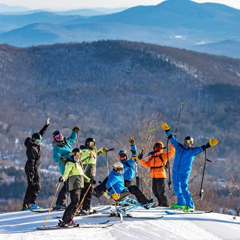 A group of skiers waving at the camera