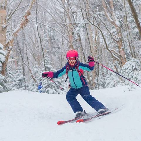 A little girl skiing in the woods