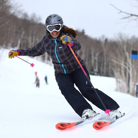 A women smiling and skiing