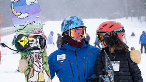 A little boy snowboarding with an instructor