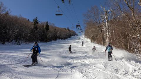 A group skiing freestyle down cliffs