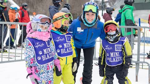 An instructor and a group of Mini Blazers smiling at the camera