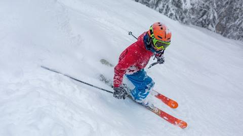 A boy smiling and skiing at the camera