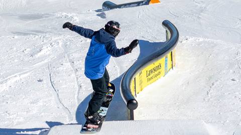 A kid hitting a rail snowboarding
