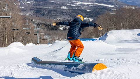 A kid hitting a rail snowboarding