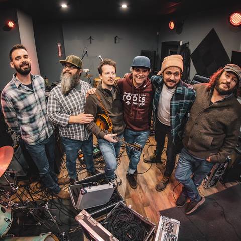 The band Cabinet standing together in a recording studio