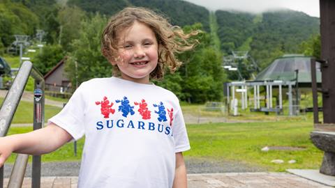 A little girl smiling with a Sugarbush T-shirt on 