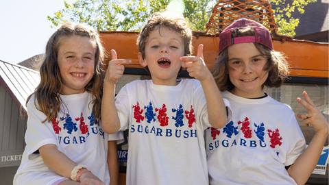 A group of kids smiling posing for a photo with 4th of july t-shirts on