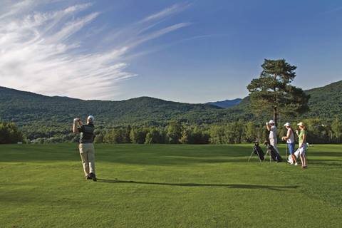 Golfer teeing off with three spectators