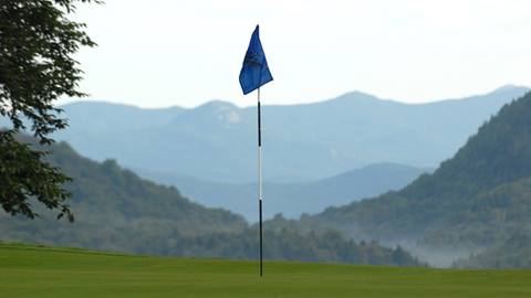 Golf flag in a hole with a scenic backdrop
