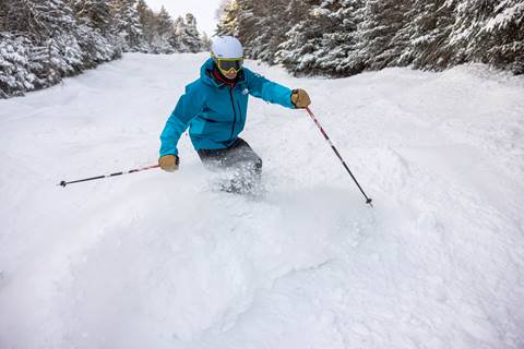 Skier in blue jacket slashing powder