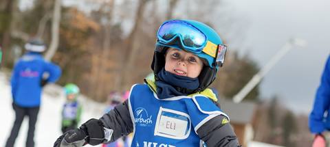 A little boy in ski attire smiling at the camera