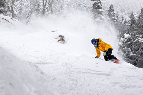 A snowboarder with powder behind them 