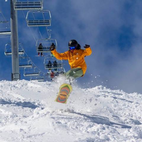 Snowboarder ripping powder on Ripcord with bluebird weather