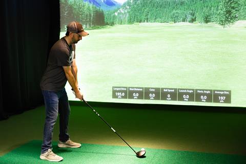 Teeing up to swing at an indoor golf simulator