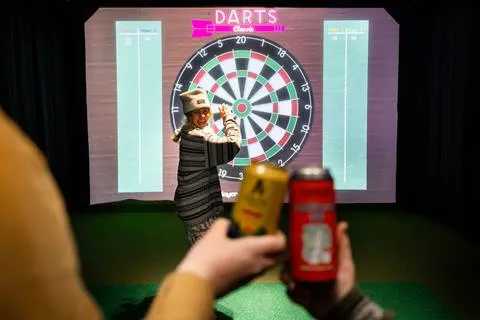 Cheers in front of a Sports simulator dart board