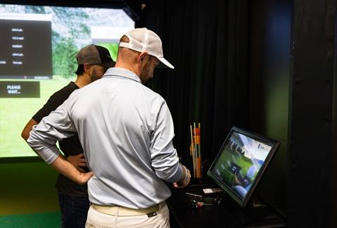 roger helping matt with golf stats in simulator