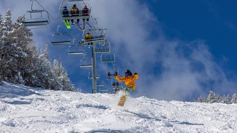 A guy in a yellow jacket ripping down Ripcord under a blue sky. 