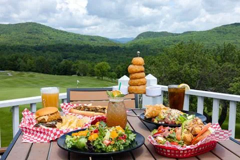salads and sandwiches with drinks on table overlooking golf course
