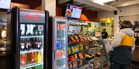 skier in mt ellen cafeteria looking at menu near snacks