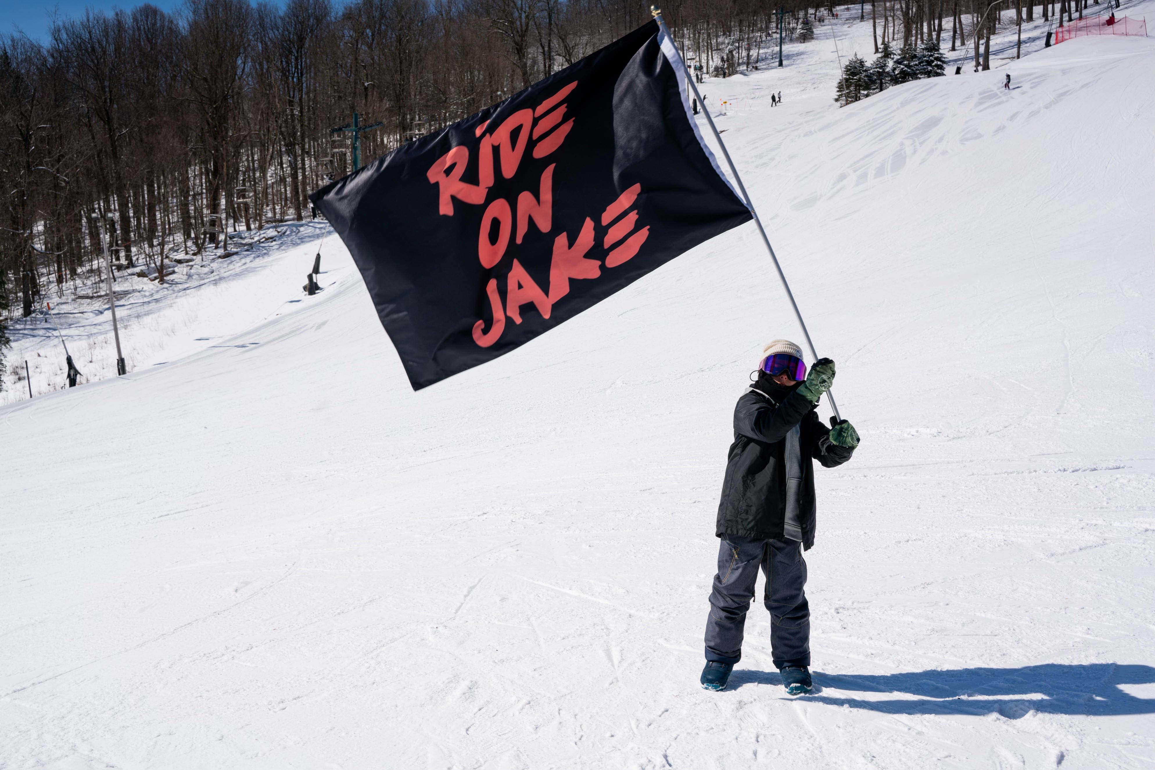 Snowboarder with Ride for Jake flag