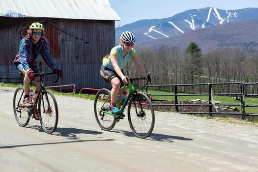 2 bikers riding with mountain in background