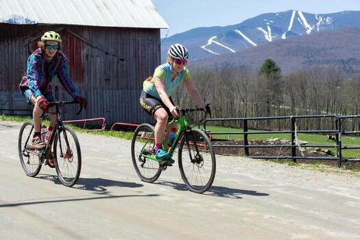 2 bikers riding with mountain in background