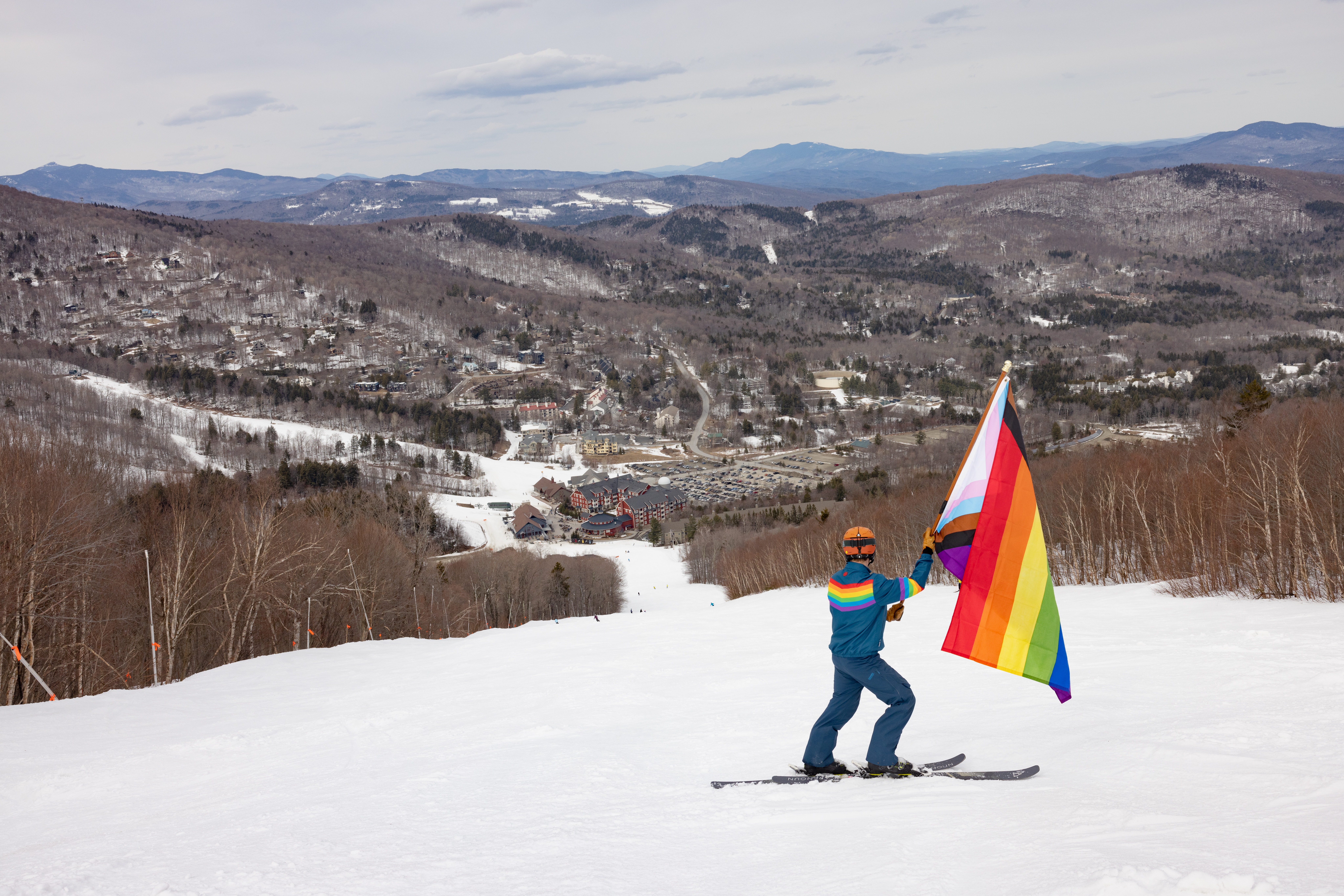 Joel holding pride flag top of trail looking at village